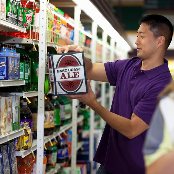 Um homem em um supermercado olhando para uma caixa de cerveja