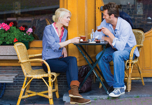 Dos personas sentadas al aire libre bebiendo café