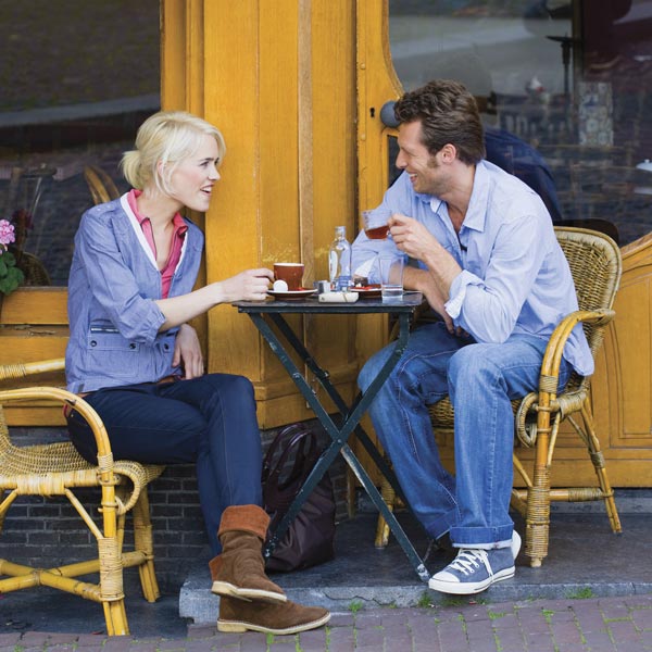 Duas pessoas sentadas no exterior a beber café