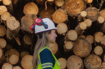 woman standing in front of tree logs