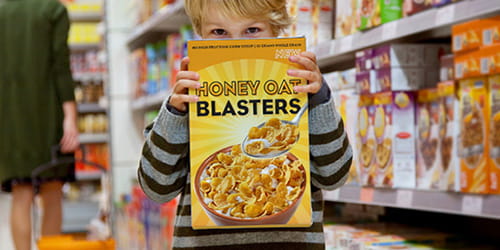 Jeune garçon tenant un paquet de céréales dans une allée d’épicerie