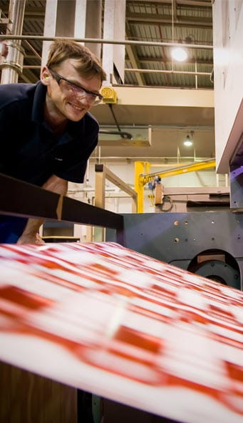 Un homme dans une usine, regardant un rouleau de papier