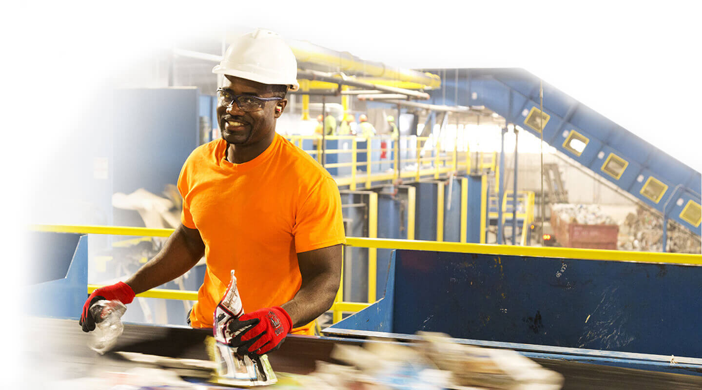 A man in an orange shirt working an a recycling plant.