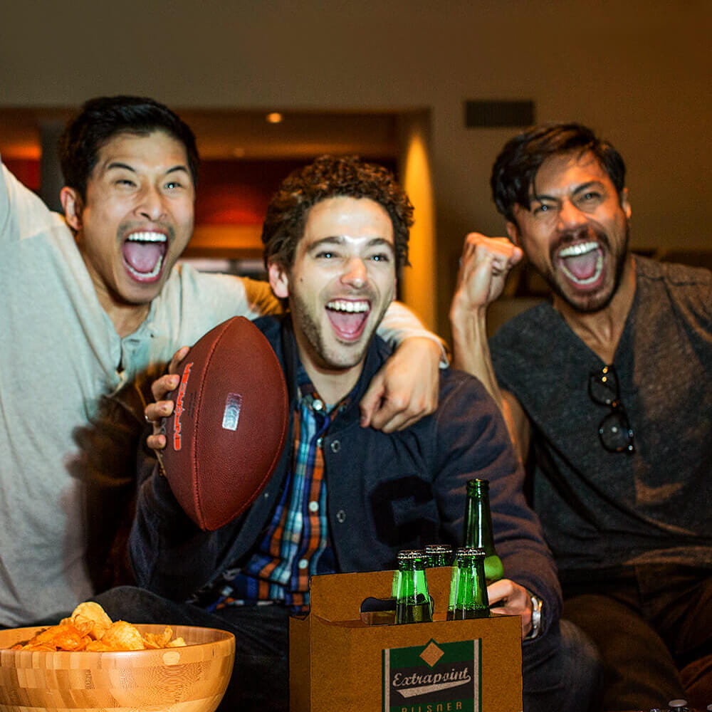 foto de três homens no sofá assistindo esportes e bebendo cerveja