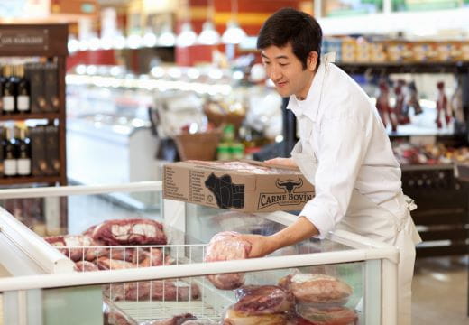 Store employee stocking meat in grocery store