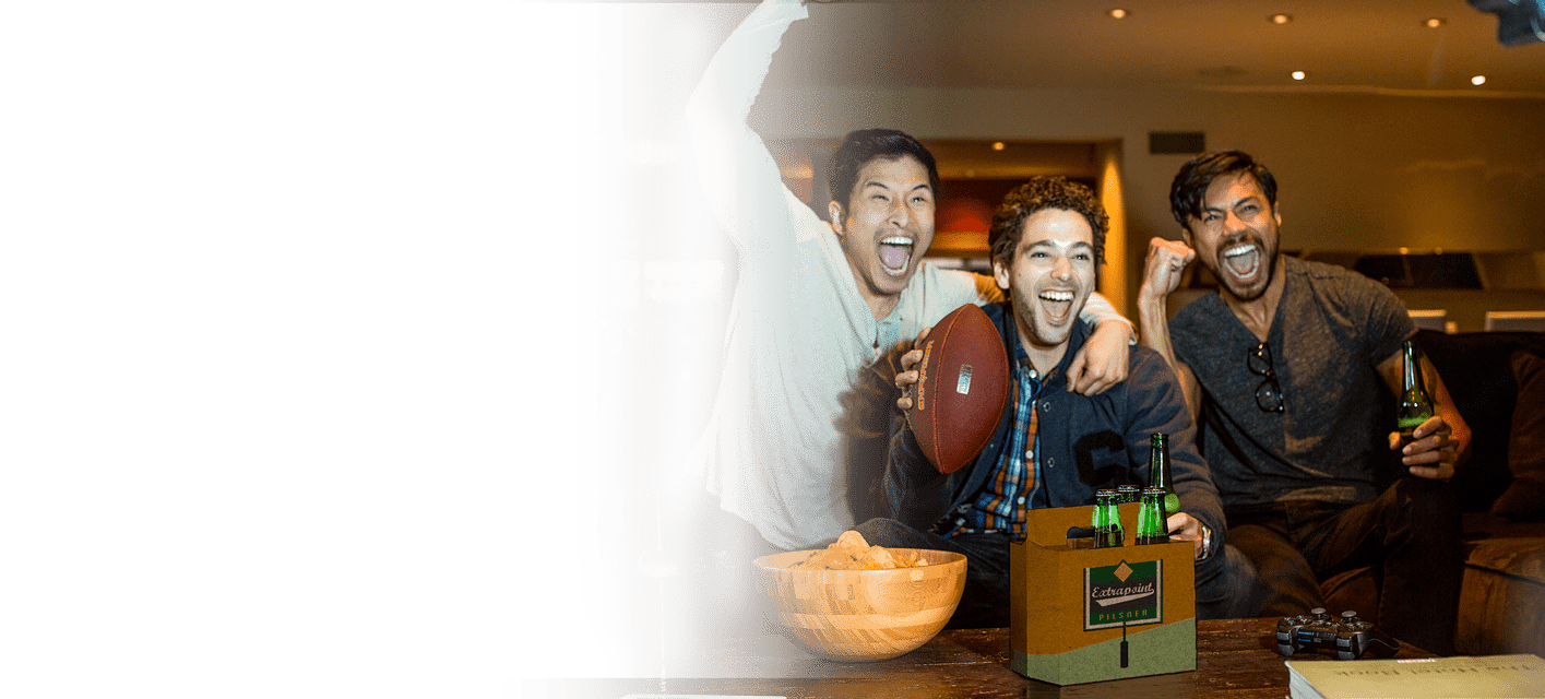 grupo de homens assistindo a futebol americano com uma embalagem de seis cervejas