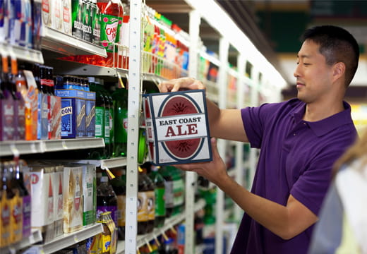A man in a grocery store looking at a case of beer