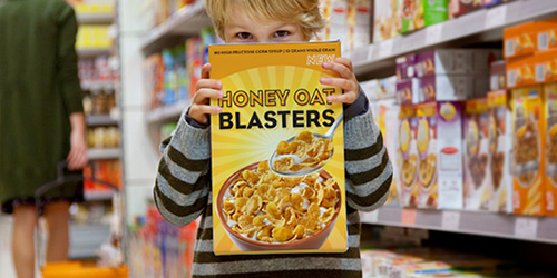 Young boy holding cereal package in grocery aisle