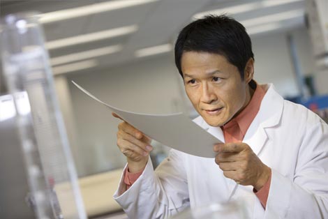 A man in a lab looking at a sheet of paper.